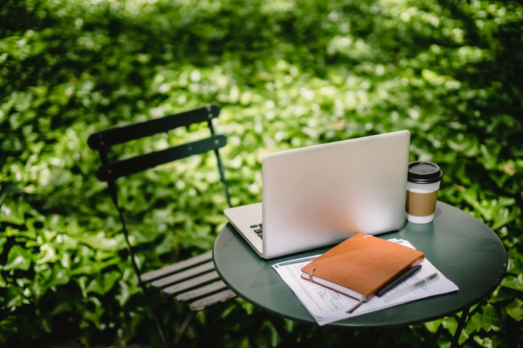 cozy table with laptop and notebook in park